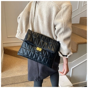 Detail of black quilted leather shoulder bag with gold twist lock and chain strap