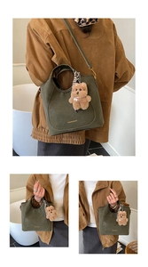 Detail view of olive green bucket bag with plush bear charm and fashion text logo