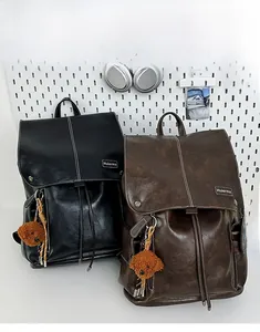 Detail of vintage leather backpacks in black and brown with contrast stitching and charms