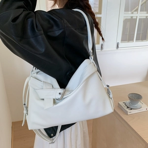 White minimalist pebble leather tote bag with buckle detail shown on a model in a cozy setting
