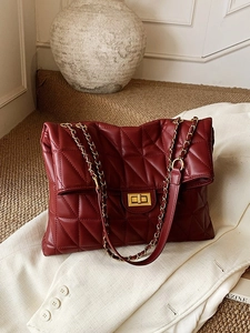 Quilted burgundy chain shoulder bag with gold twist lock on a white blazer