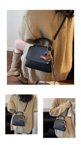 Close-up of black litchi grain leather bag with heart lock pendant and silver hardware