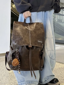 Large vintage dark brown leather backpack with drawstring closure and white stitching detail