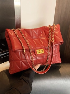 Red quilted leather chain bag with triangle stitching and gold clasp on dark leather seat