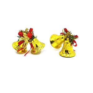 Nahaufnahme goldener Weihnachtsglocken mit roten Schleifen, Tannennadeln und Engel-Deko