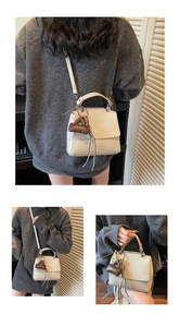 Close-up of cream textured leather handbag with a miniature brown charm accessory