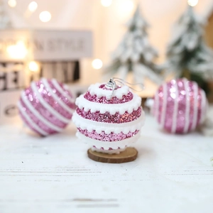 Pink glitter Christmas ornaments with white wave pattern on wood base and bokeh background