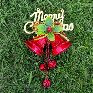 Close-up of red Christmas bells with gold Merry Christmas sign and green holly leaves