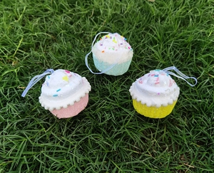 Vue détaillée de suspensions de Noël en forme de cupcakes colorés avec paillettes sur gazon