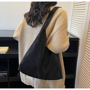 Minimalist black matte leather hobo bag with wide shoulder strap on model in cozy interior