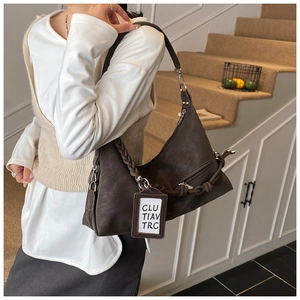 Détail d'un sac hobo marron foncé avec anse tressée épaisse et fermeture éclair en métal