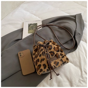 Detail of leopard print faux fur bucket bag with brown leather strap and drawstring bow