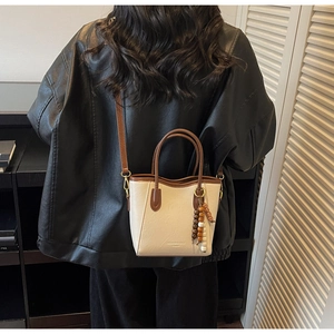 Détail du sac seau rétro avec breloque en perles de bois sur veste en cuir