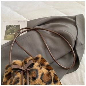 Detail of leopard print faux fur bucket bag with brown bow and leather strap