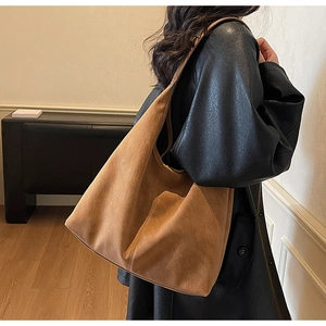 Detail of caramel suede large tote bag with wide strap on black leather coat