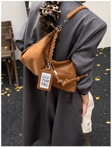 Sac hobo marron avec anse tressée et détail de gland porté par un mannequin
