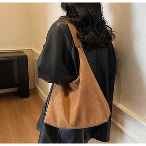 Detail of a large brown suede hobo bag with natural slouchy folds and a retro minimalist look
