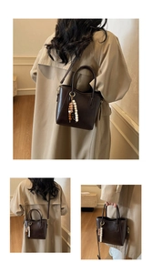 Détail d'un sac seau en cuir marron foncé avec breloque en perles et bandoulière