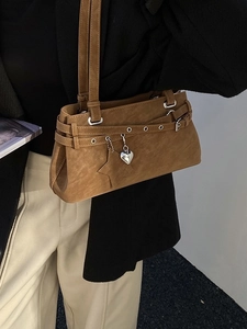 Braune matte Umhängetasche mit Herzanhänger an Model in schickem minimalistischem Outfit