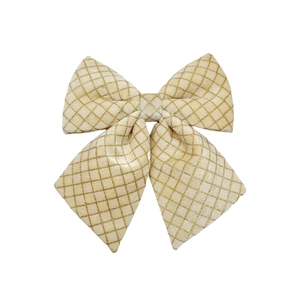 Macro detail of champagne quilted Christmas bow with gold diamond pattern for tree decor