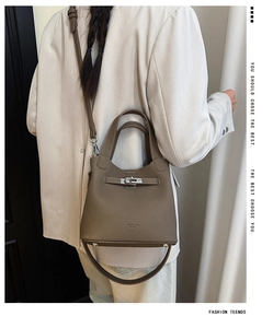 Detail of tan leather bucket bag with lychee texture and adjustable shoulder strap on model