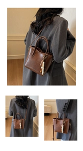 Détail d'un sac cabas marron vintage avec pendentif en bois et logo de mode