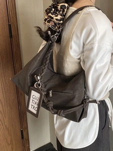 Sac à bandoulière marron foncé tendance avec sangle tressée porté à l'épaule