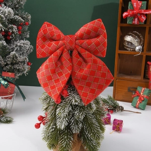 Detail of red Christmas bow with gold stitching on cedar tree with berries decor