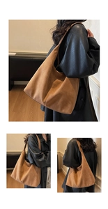 Detail of a large brown suede hobo tote bag featuring center vertical stitching and soft texture