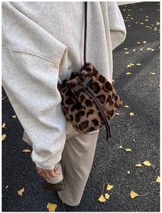 Macro detail of leopard faux fur bucket bag featuring brown leather drawstring bow tie
