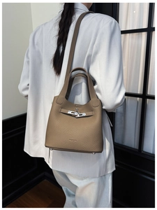 Detail of khaki leather bucket bag with metallic twist lock and pebbled texture surface