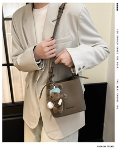 Sac seau en cuir litchi marron avec bijou d'ours porté à l'épaule par un mannequin