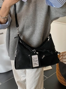 Sac demi-lune chic en daim noir avec bandoulière tressée et étiquette lettrée élégante