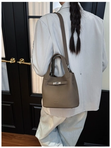 Detail of lychee textured leather bucket bag with metal buckle and shoulder strap