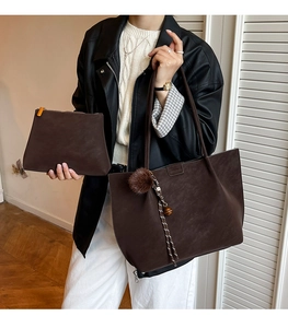 Detail of dark brown suede tote bag set with pom-pom charm and matching clutch pouch