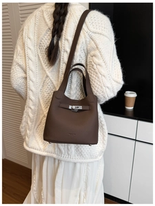 Rear view of a model wearing a dark brown lychee leather bucket bag with silver clasp