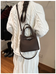 Detail of dark brown pebble leather bucket bag with silver buckle and long shoulder strap