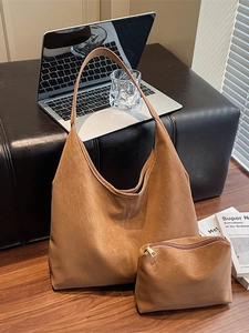 Minimalist tan leather tote bag set with matching pouch in a modern office setting
