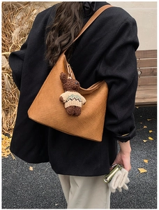 Detailed texture of brown woven hobo bag with a cute bear charm in autumn setting