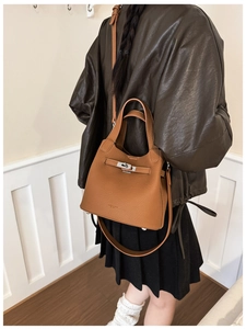 Detailed view of brown lychee grain leather bucket bag styled with a dark coat
