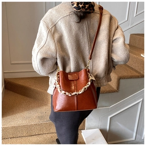 Close-up of retro brown bucket bag with a silk scarf chain strap and pleated details