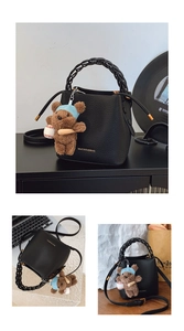 Détail du sac seau en cuir grainé noir avec poignée tressée et charm d'ours peluche