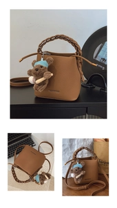 Détail d'un sac seau en cuir marron avec poignée tressée et charm d'ours mignon