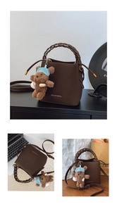 Détail du sac seau marron foncé avec poignée tressée et breloque ours en peluche