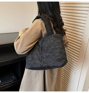 Detail of black pleated tote bag showing rich fabric texture and modern casual style