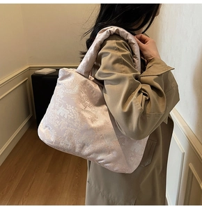 Detail view of pink quilted satin puffer tote with traditional embroidery on shoulder