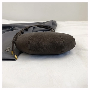 Detail of dark brown faux suede round bag with drawstring strap and gold metal hardware