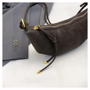 Detailed close-up of a dark brown suede croissant bag with premium gold metal zippers