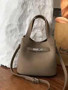 Minimalist taupe lychee leather bucket bag with top handle and adjustable shoulder strap