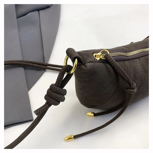 Detailed close-up of dark brown suede-texture leather bag with golden metal ring and knot